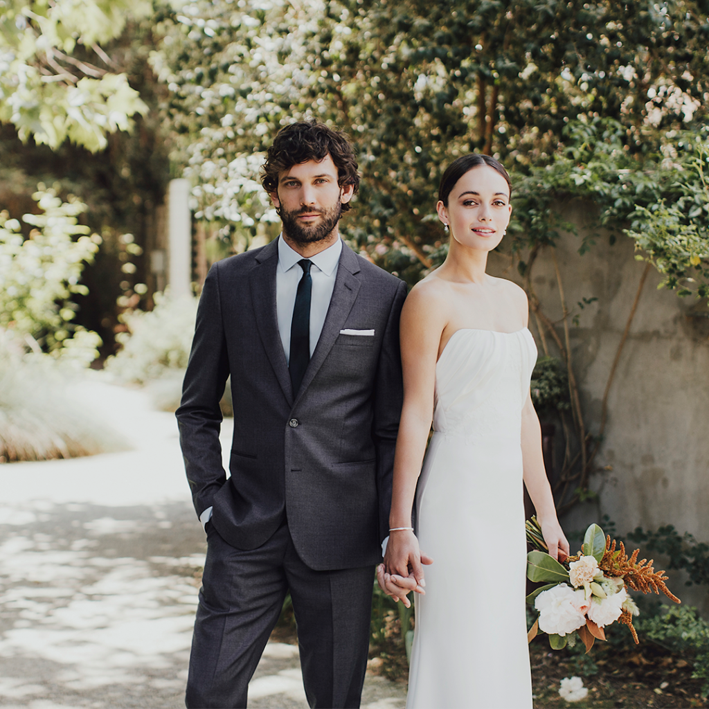 Man in charcoal suit by The Black Tux with bride in white dress.