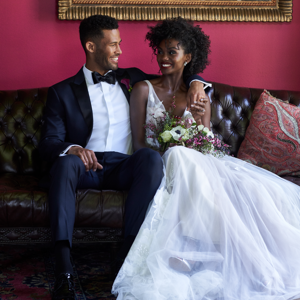 Groom in midnight blue wedding tuxedo with bride in white gown.