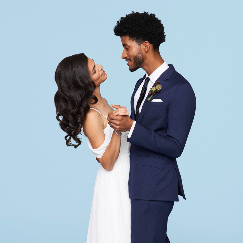 Groom dancing with bride in blue wedding suit.