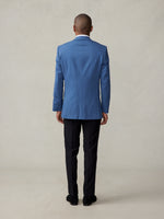 Man wearing a blue suit and black pants, viewed from the back.