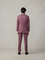 Man wearing a mauve suit, viewed from the back, standing on a neutral background.