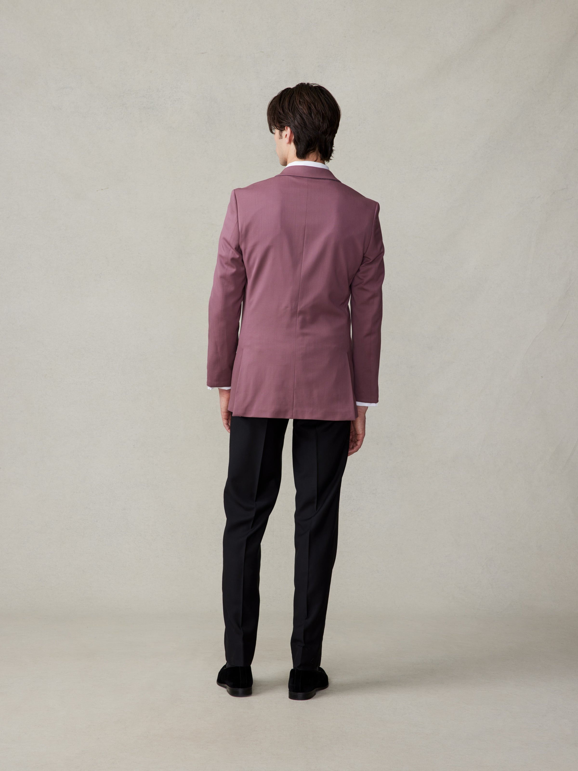 Person wearing a pink suit jacket and black pants, viewed from the back.