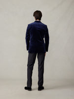 Back view of a man in an ocean blue velvet tuxedo jacket with black tuxedo pants.