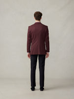 Man wearing a maroon suit jacket and black trousers, viewed from the back.