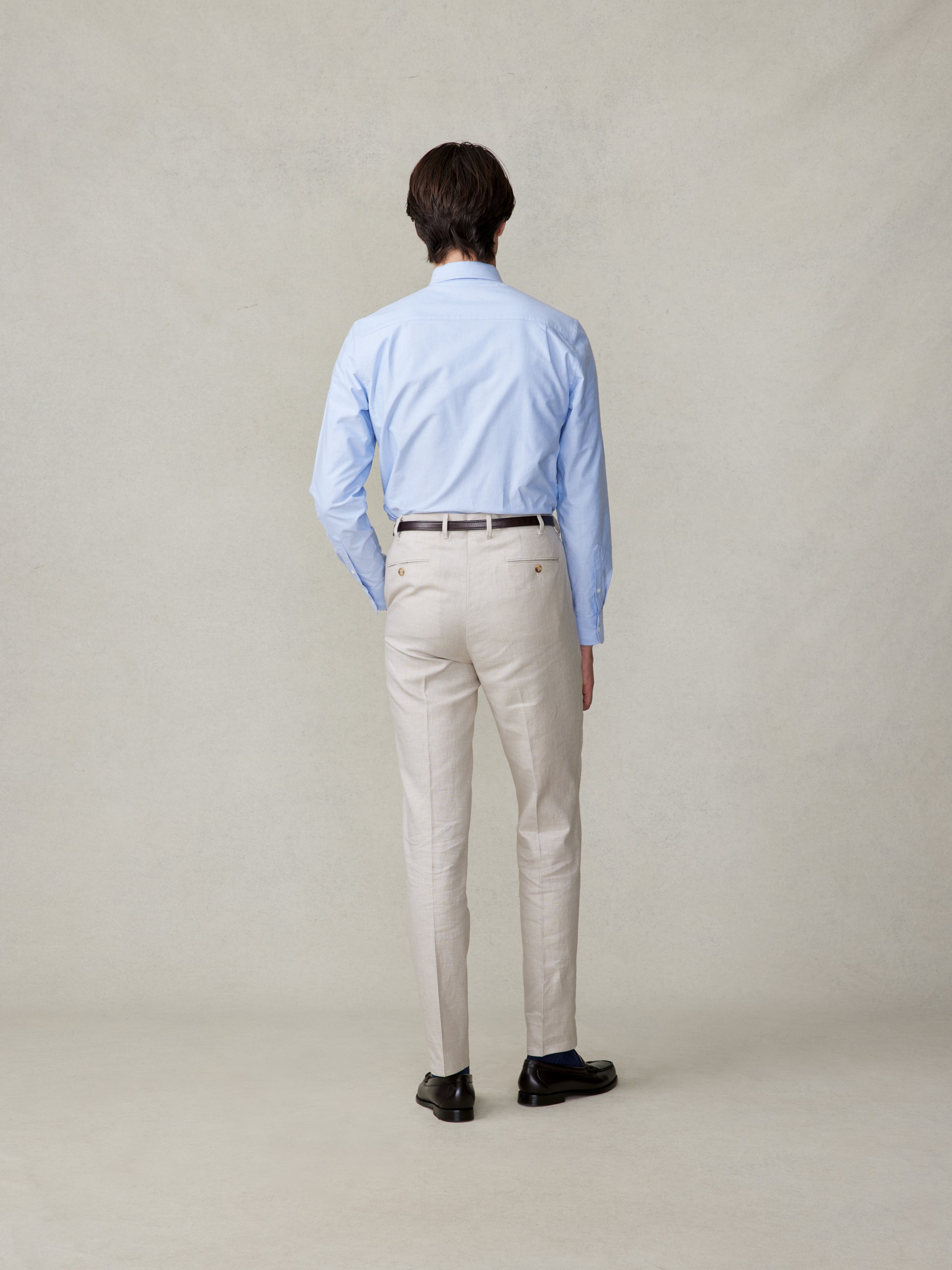 Man wearing a light blue shirt and beige pants, viewed from the back.