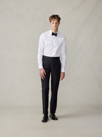 Model wearing a white dress shirt, black bow tie, and black trousers.