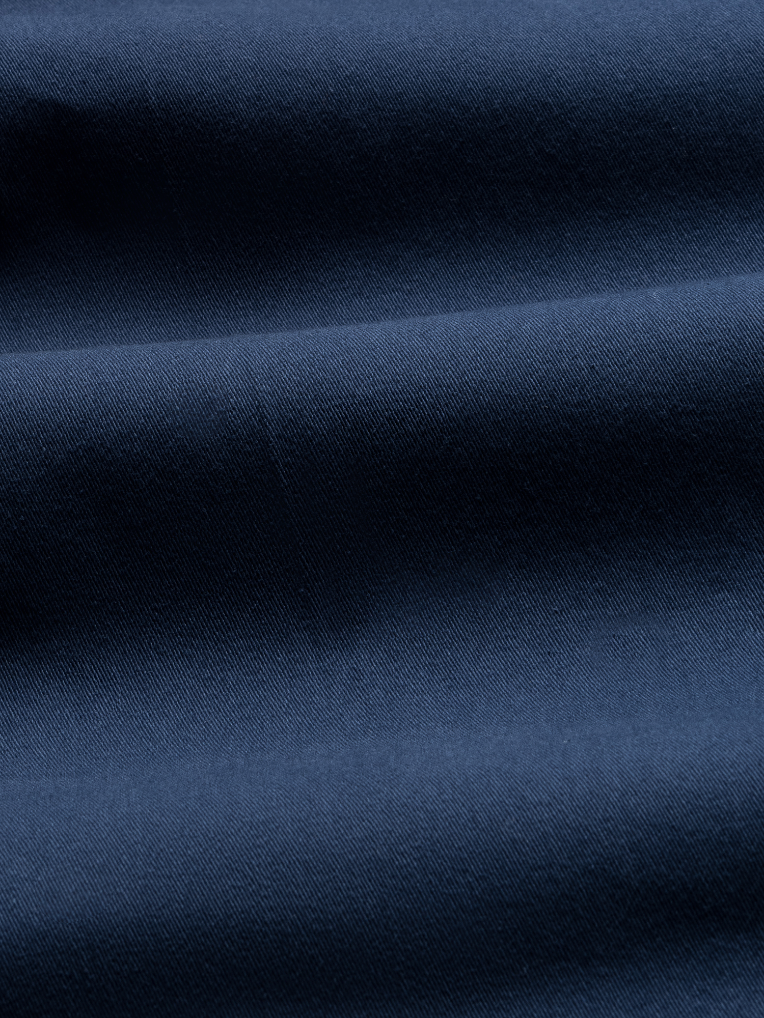 Close-up of navy chino fabric with folds, showing twill texture