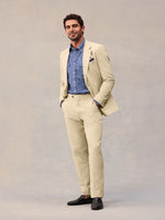 Editorial shot of harvest tan suit jacket worn open over a chambray shirt, hands in pockets
