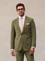 Vintage olive suit jacket buttoned over a white shirt and tan tie, cropped at the hip