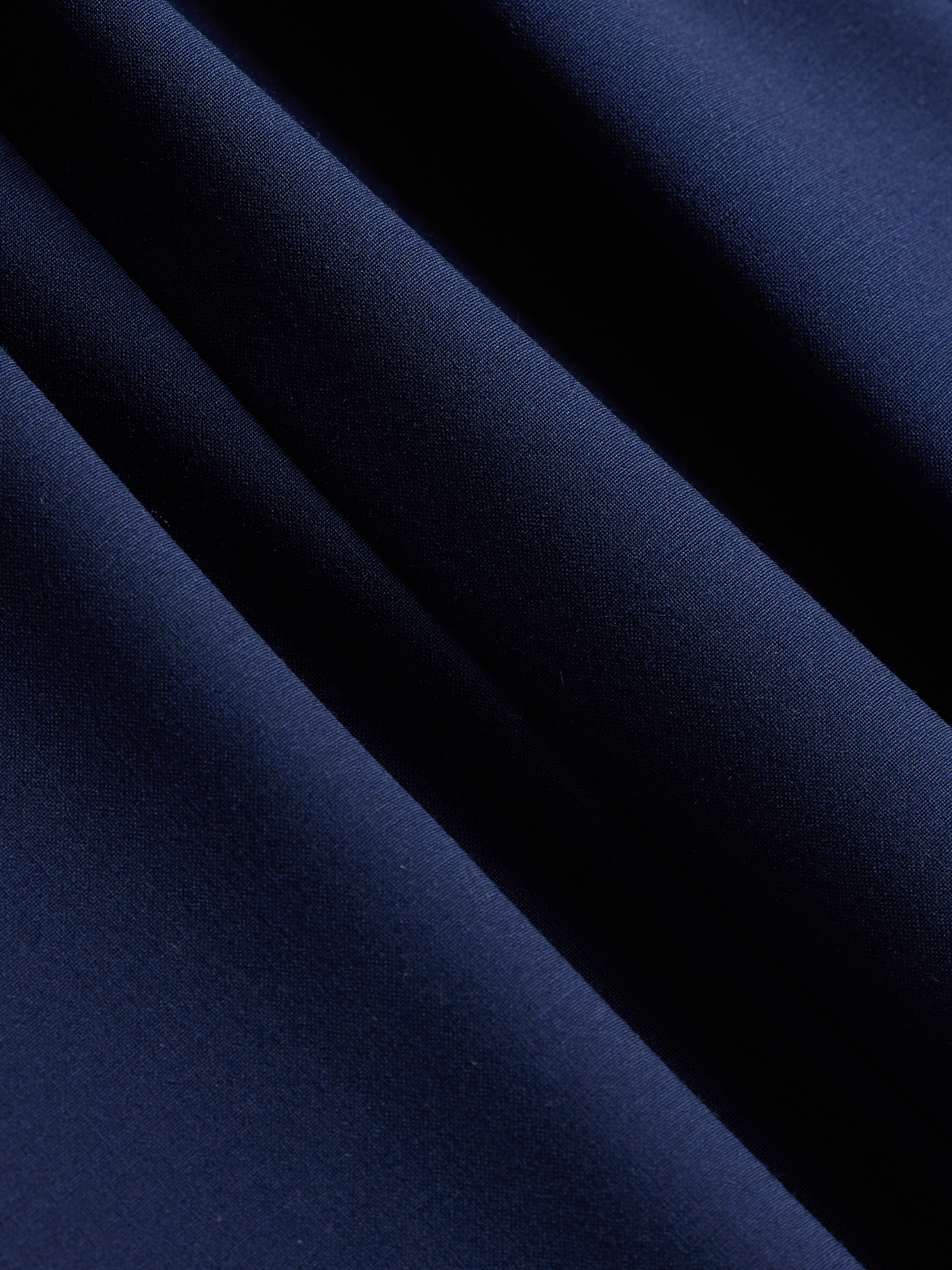 Close-up of cove blue suit fabric, a bright royal blue, draped in soft folds.