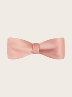 A pre-tied dusty rose satin bow tie against a light neutral background