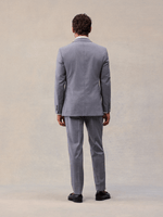 Back view of a man in a slate grey suit jacket and matching trousers, full length, black loafers.