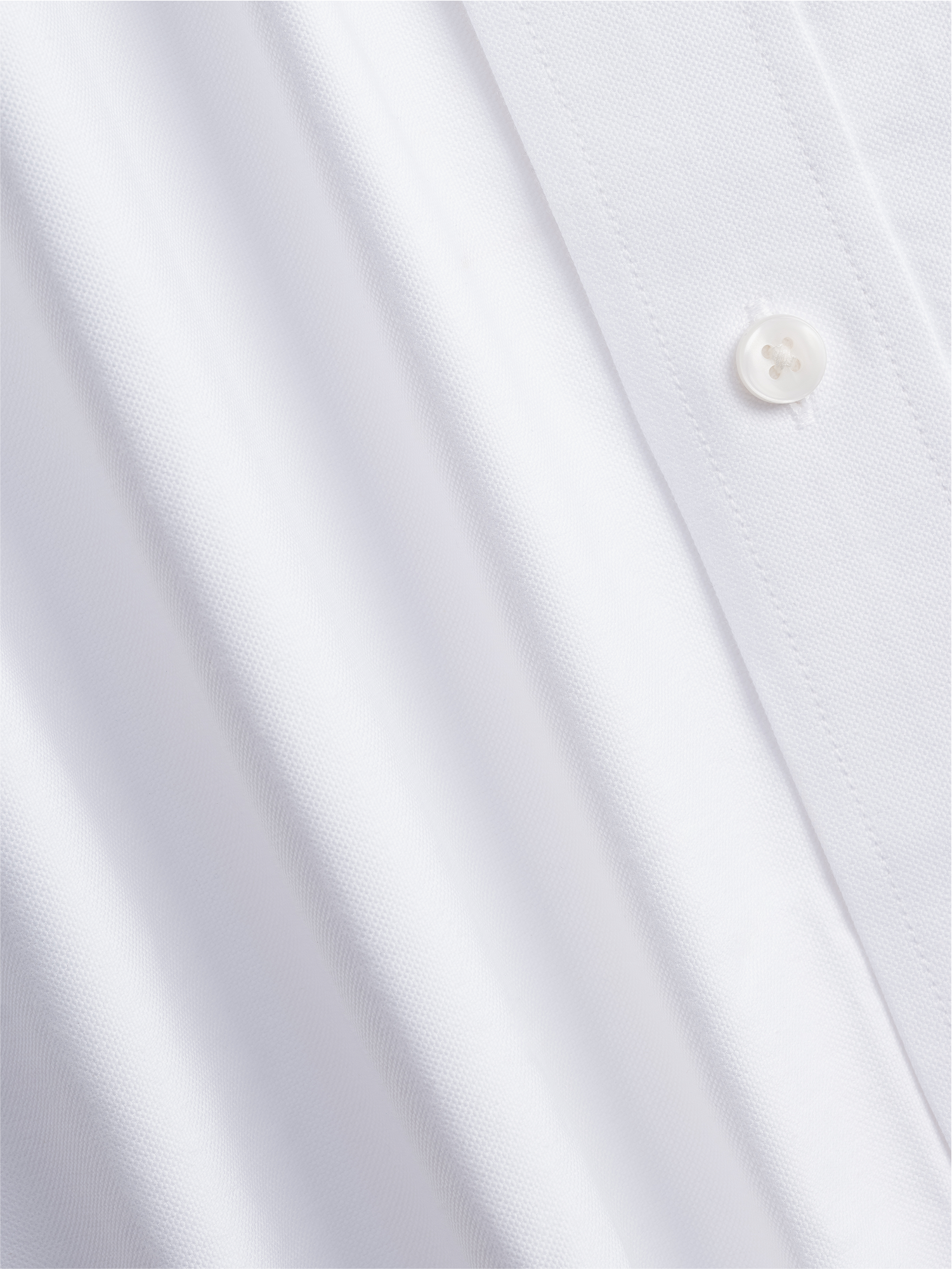 Close-up of a white shirt fabric with a button.