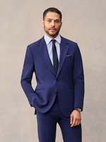 A man in a cove blue suit, a bright royal blue, with notch lapels, navy tie and brown pocket square.