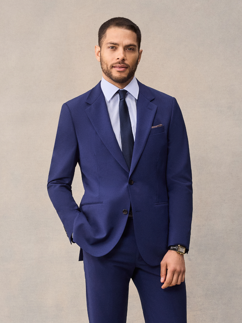 A man in a cove blue suit, a bright royal blue, with notch lapels, navy tie and brown pocket square.