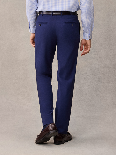 Cropped back view of cove blue suit pants with welt back pockets, light blue shirt and brown loafers.