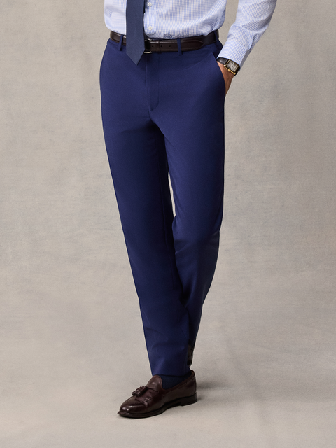 Cropped front view of cove blue suit pants with a light blue shirt, brown belt and tassel loafers.