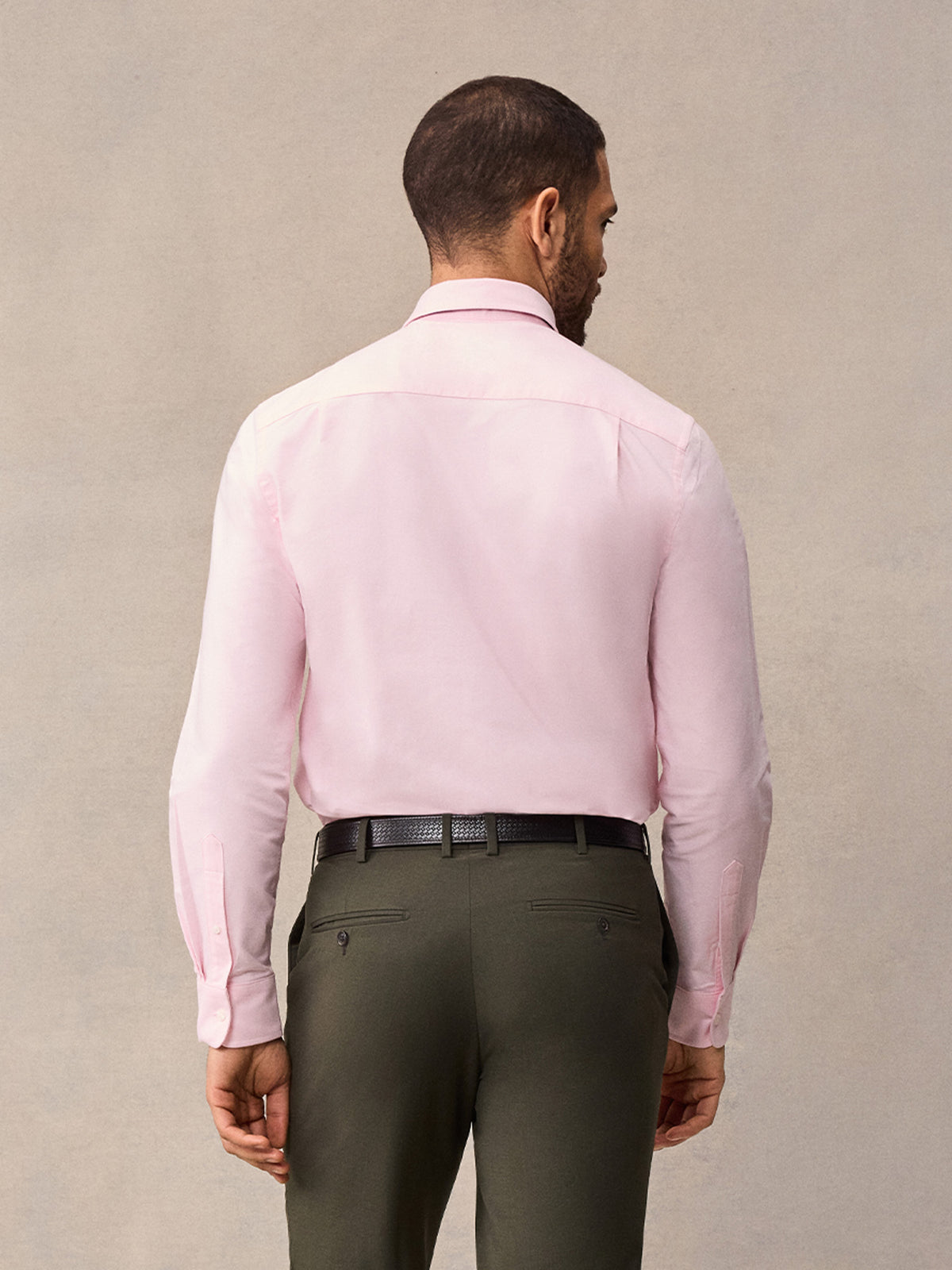 Back view of man in pink oxford shirt and olive trousers