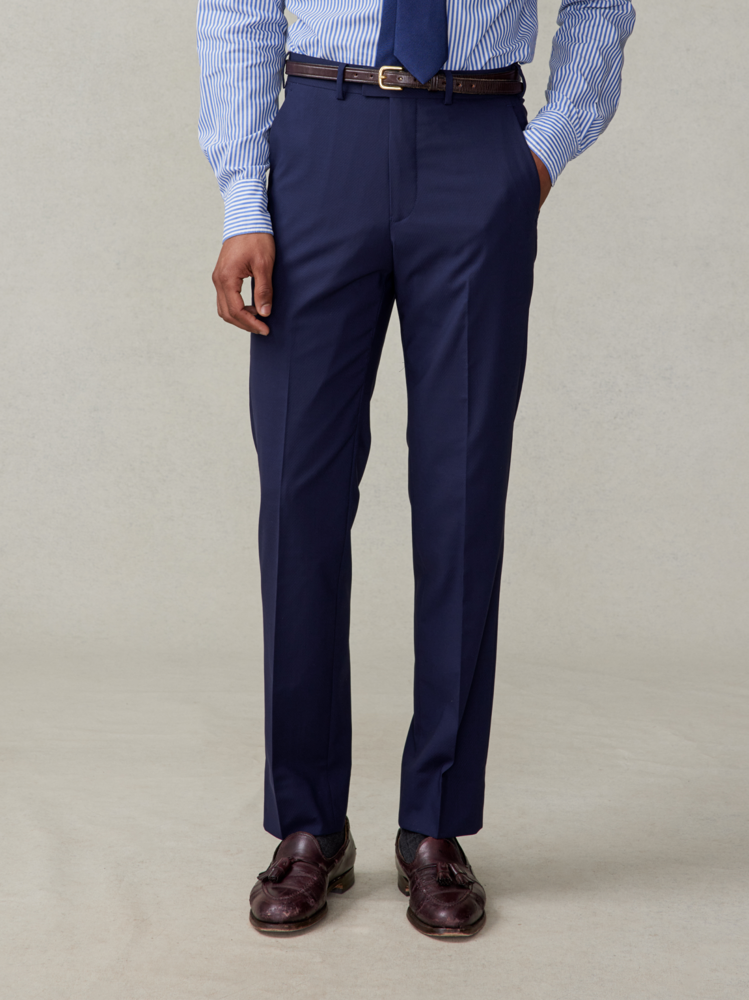 Man wearing navy dress pants, a striped shirt, and brown shoes.