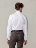 Man wearing a white shirt and brown trousers, viewed from the back.