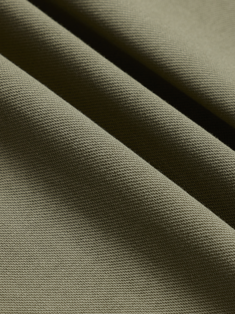Close-up of olive green pique polo fabric texture, diagonal folds