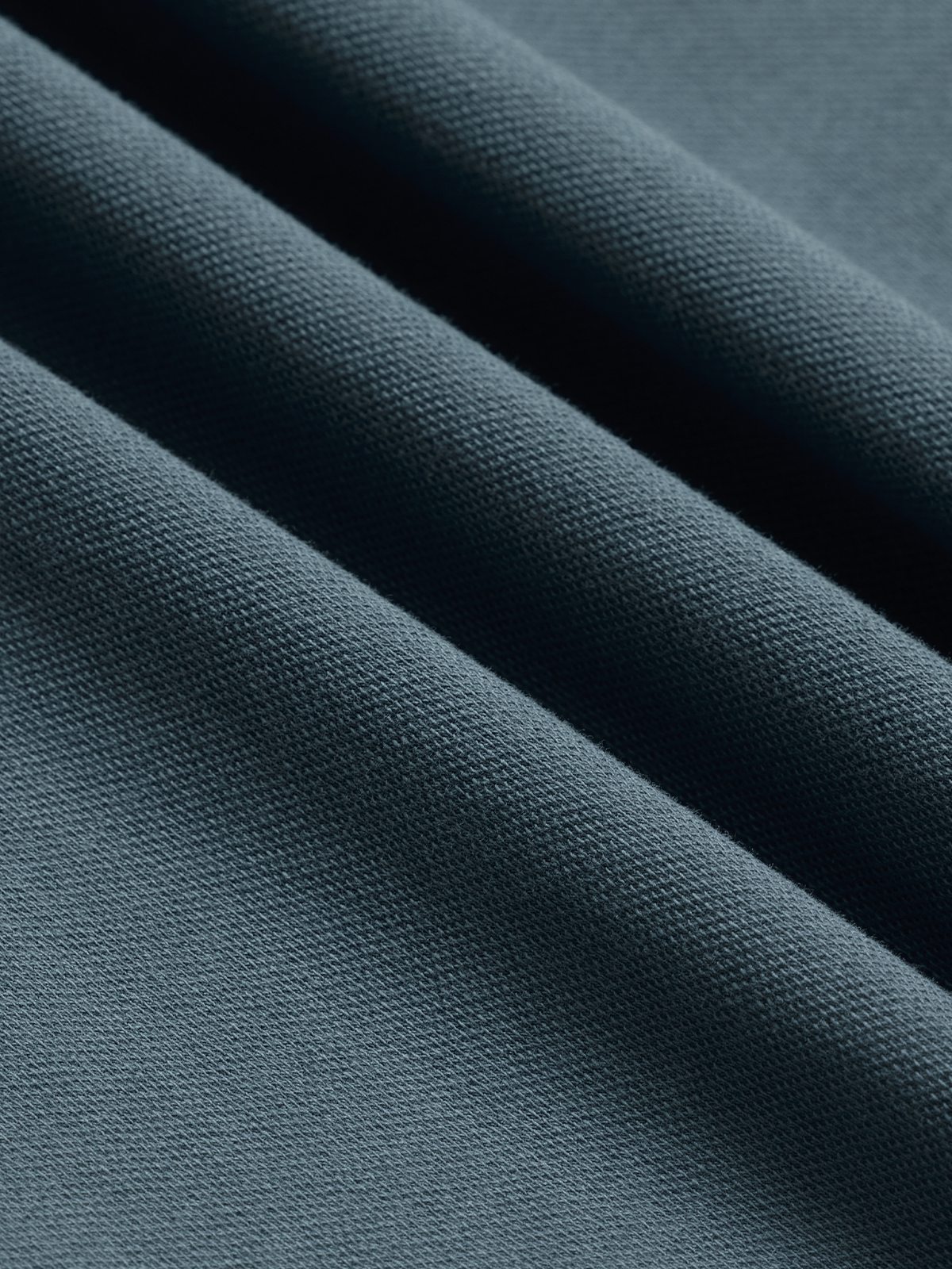 Close-up of slate blue pique polo fabric texture, diagonal folds
