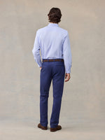 Back view of man in navy chino pants and light blue striped shirt, full length