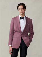Man wearing a pink tuxedo jacket with a black bow tie and black pants.