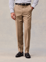 Close-up of camel flat-front suit trousers with belt loops and a pressed crease, front view.