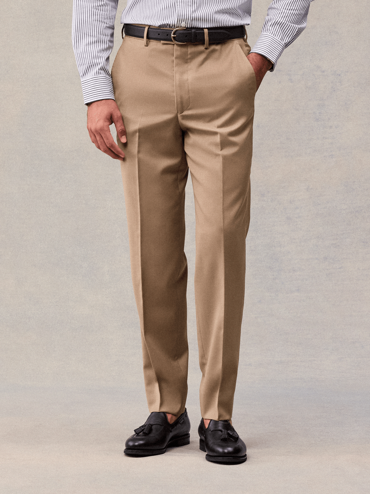 Close-up of camel flat-front suit trousers with belt loops and a pressed crease, front view.