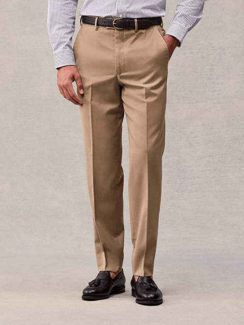 Close-up of camel flat-front suit trousers with belt loops and a pressed crease, front view.