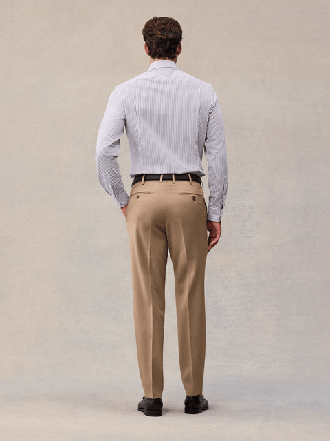 Back view of camel suit trousers with back welt pockets, worn with a black belt.