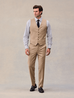 Full-length view of a model in a camel suit vest and matching trousers with navy tie.