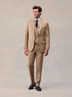 Three-quarter view of a model in a camel three-piece suit, open jacket showing the matching vest.