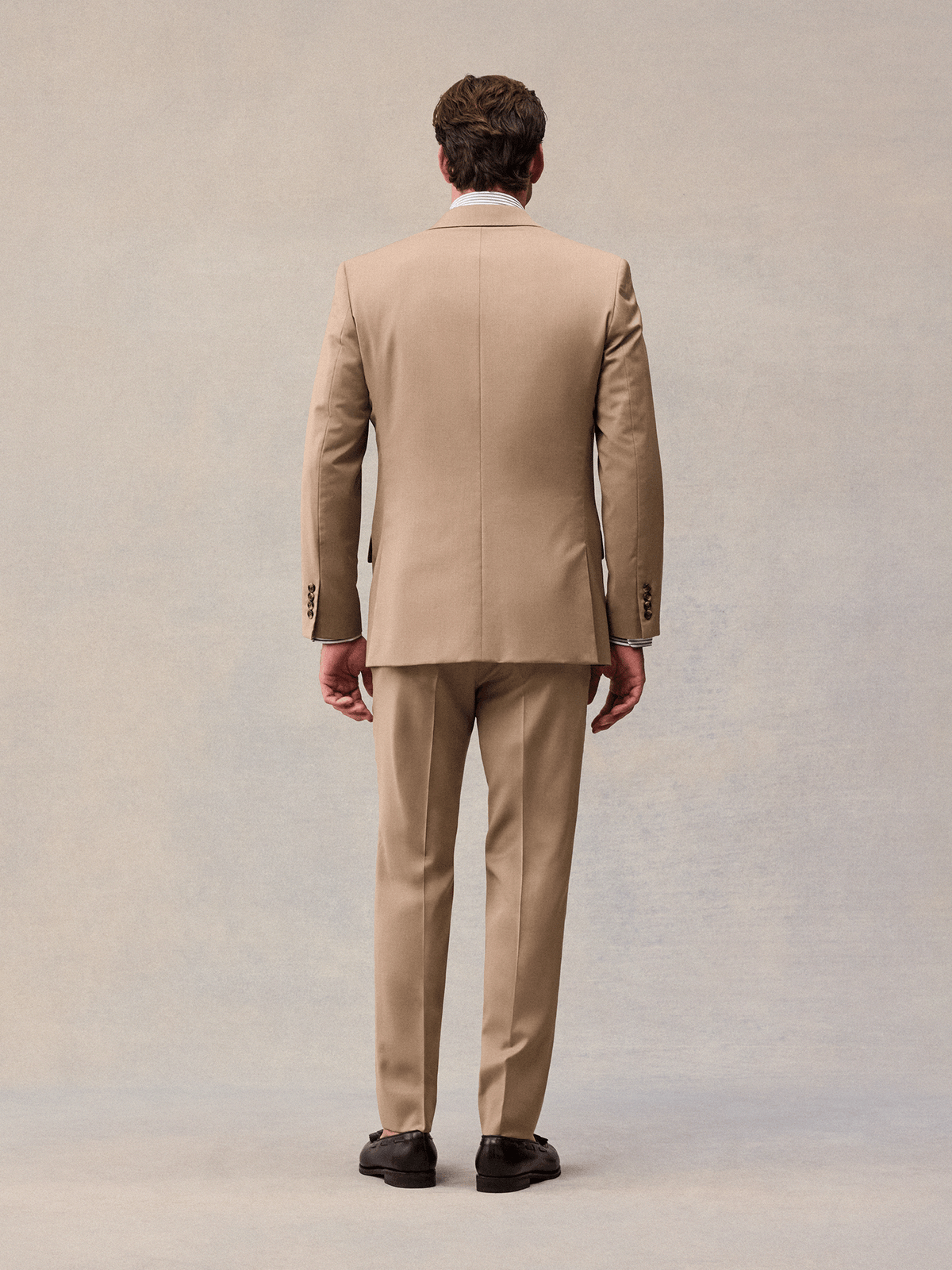 Back view of a model in a camel suit jacket and matching trousers.