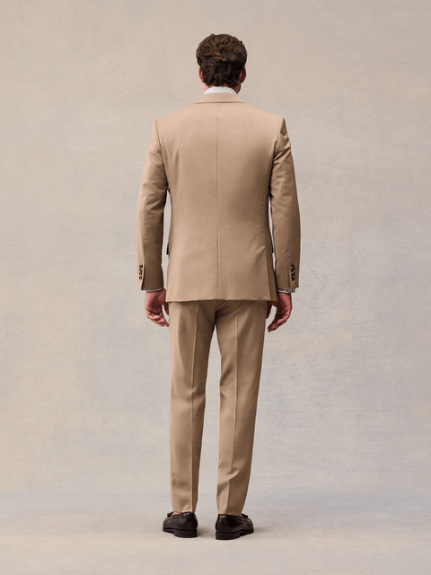 Back view of a model in a camel suit jacket and matching trousers.