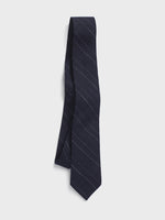 Navy tie with white stripes hanging against a white background.
