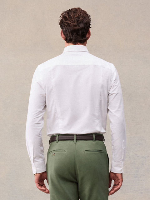 Back view of man in white oxford shirt and olive green trousers, waist-up
