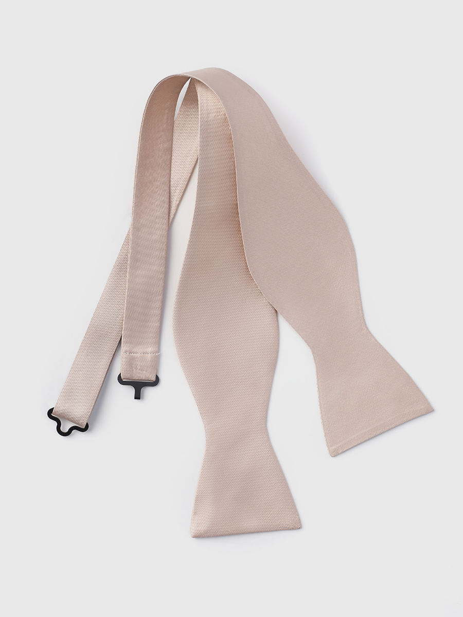 Beige bow tie with adjustable straps laid flat on a white background.