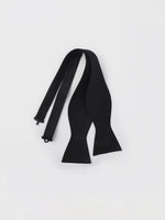 A black bow tie laid flat on a white background.