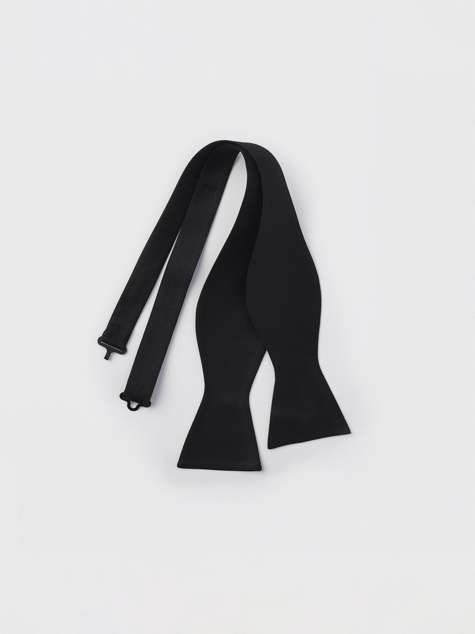 A black bow tie laid flat on a white background.