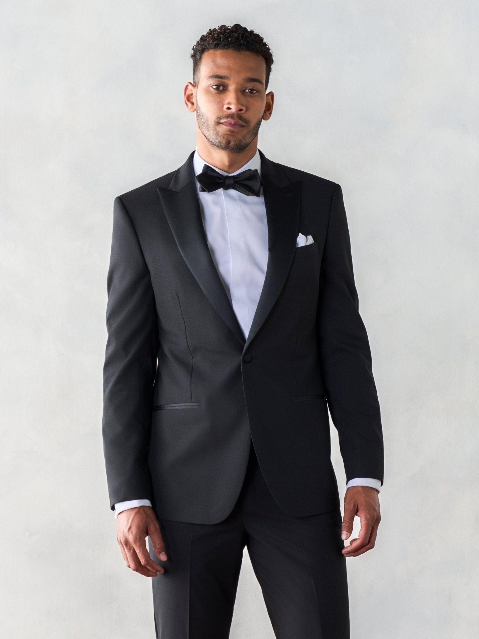 Man wearing a black tuxedo with a bow tie and white shirt.