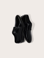 Two black patent leather dress shoes with laces, positioned on a light background.