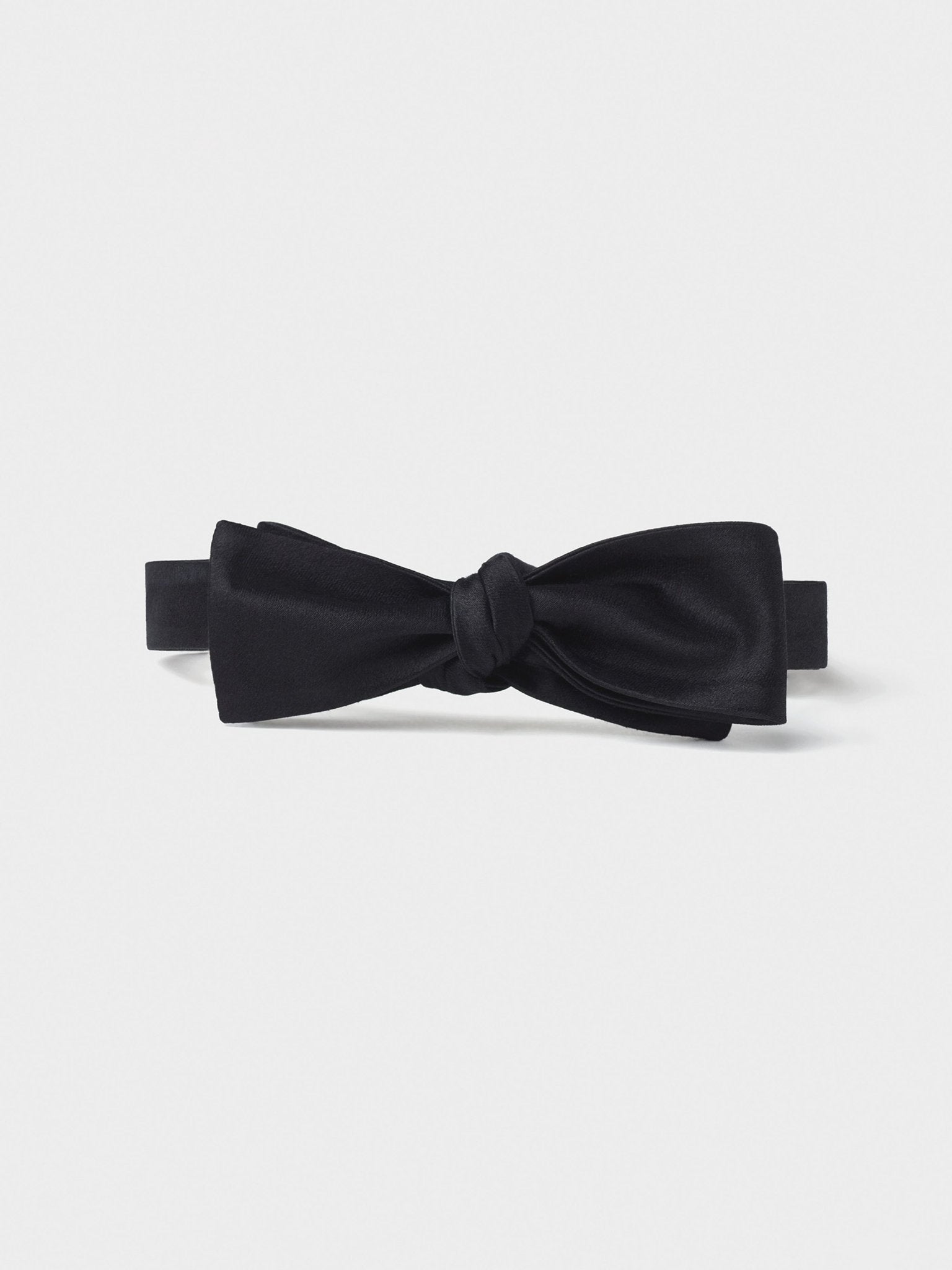 Black bow tie with a smooth texture and a knot in the center.