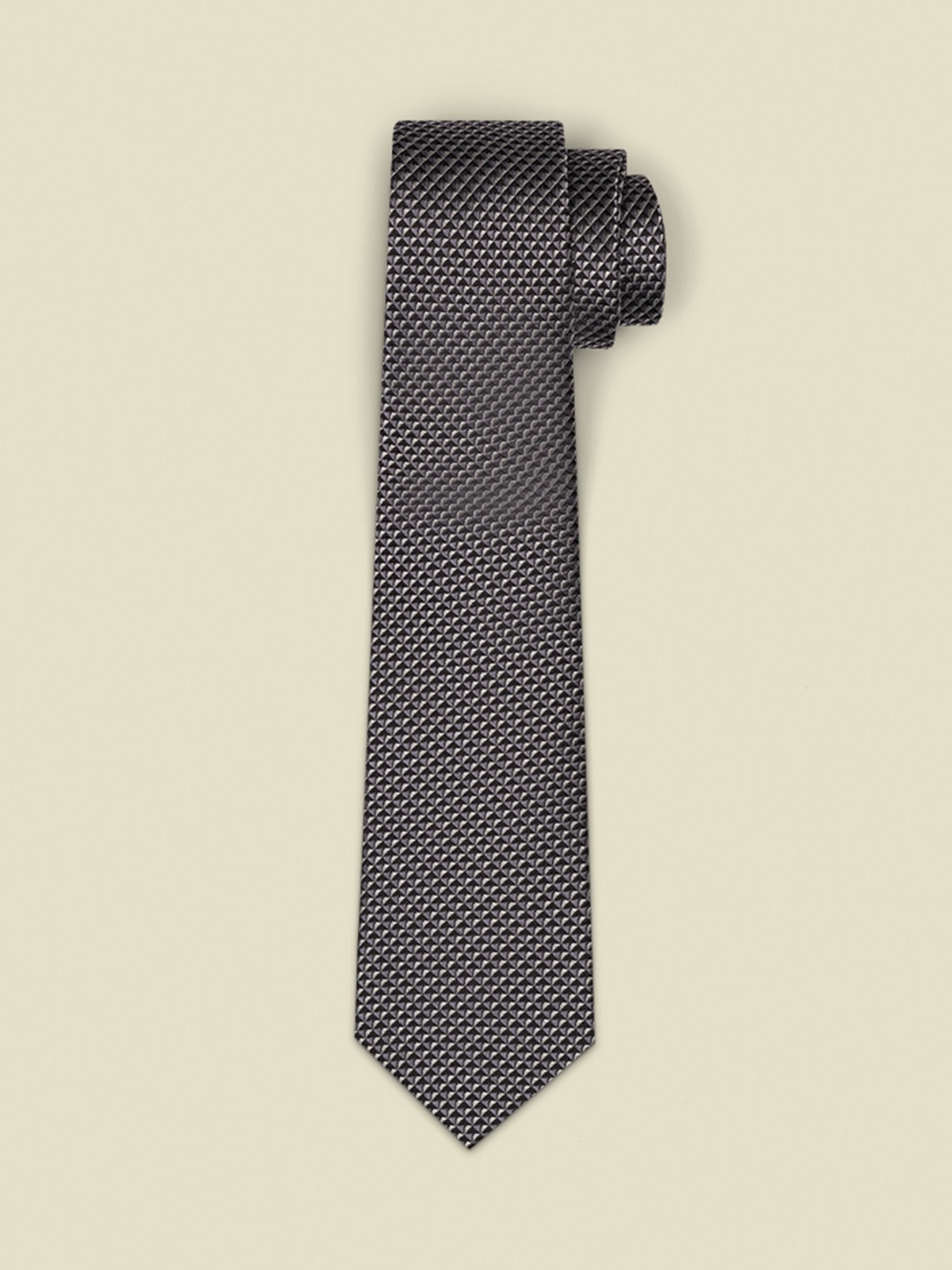 Textured black tie rolled up on a light beige background.