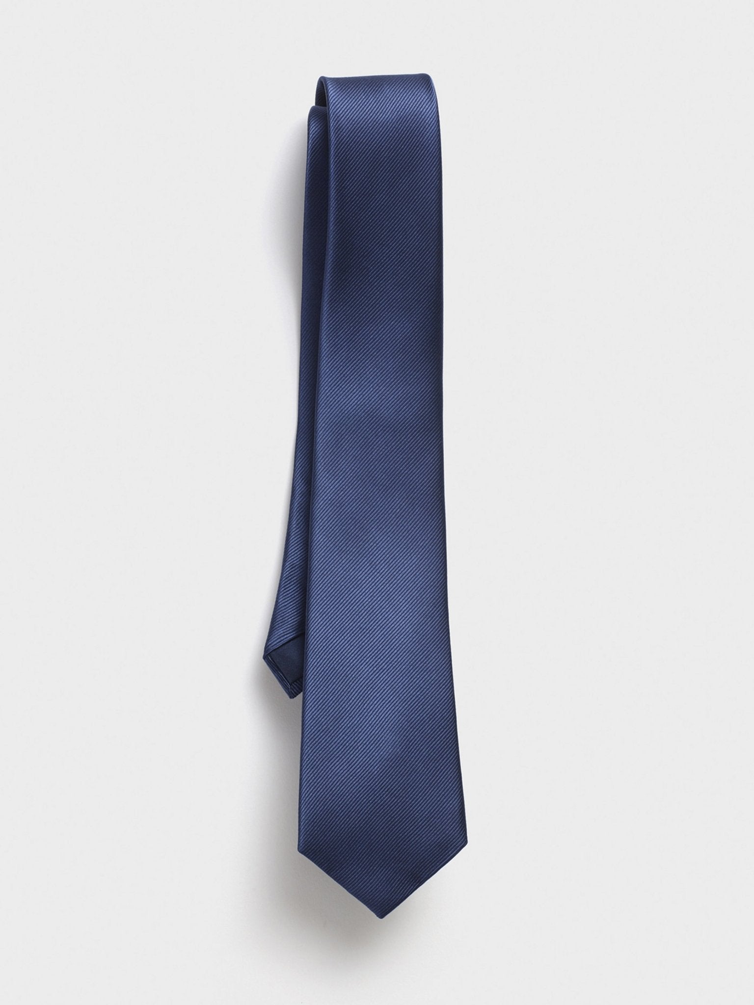 Navy tie with a textured pattern hanging against a white background.