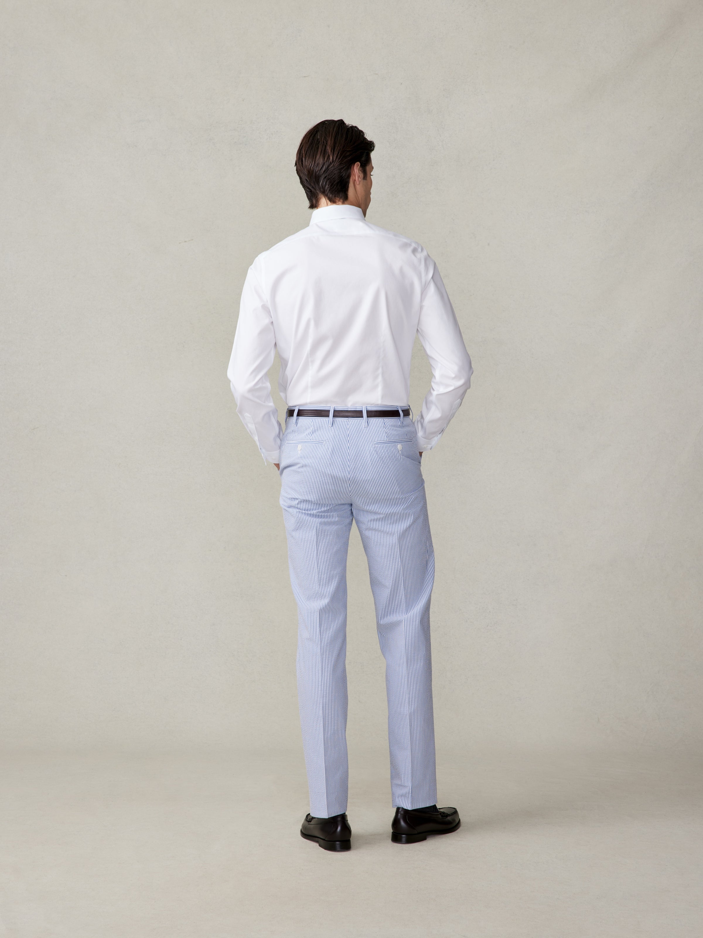 Man wearing a white shirt and striped pants, viewed from the back.