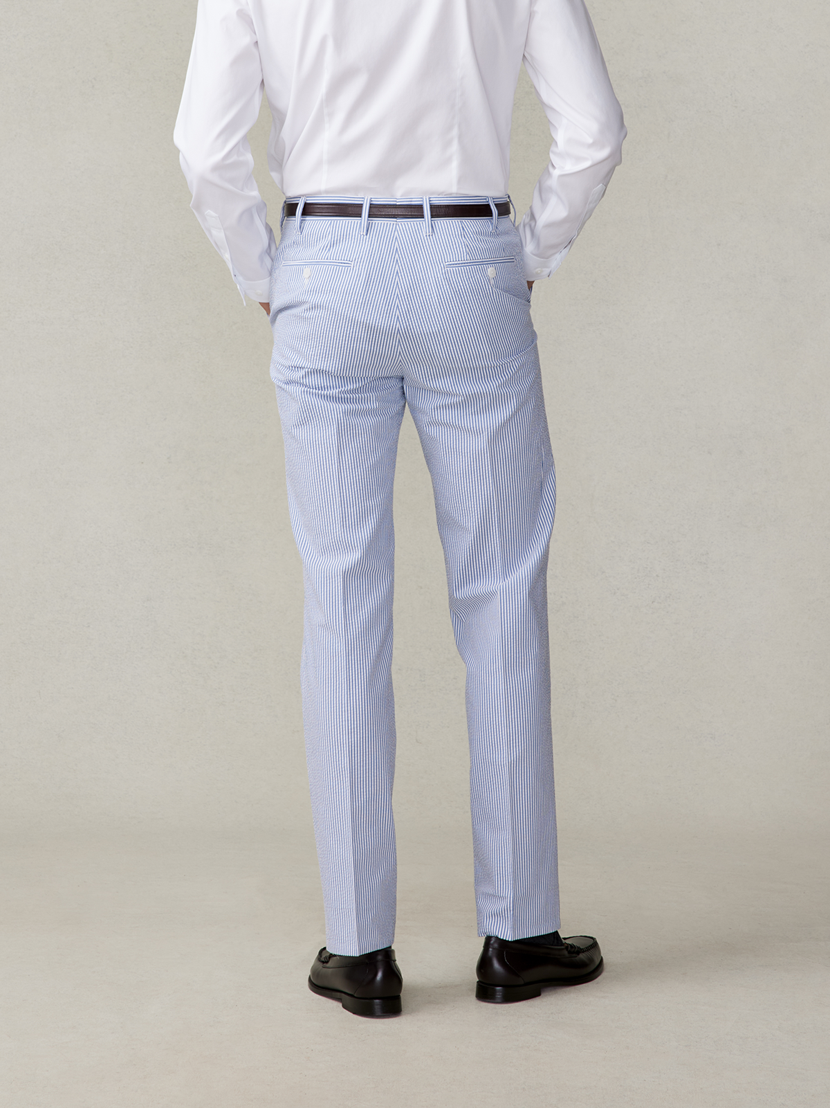 Man wearing striped blue pants and black shoes, viewed from the back.