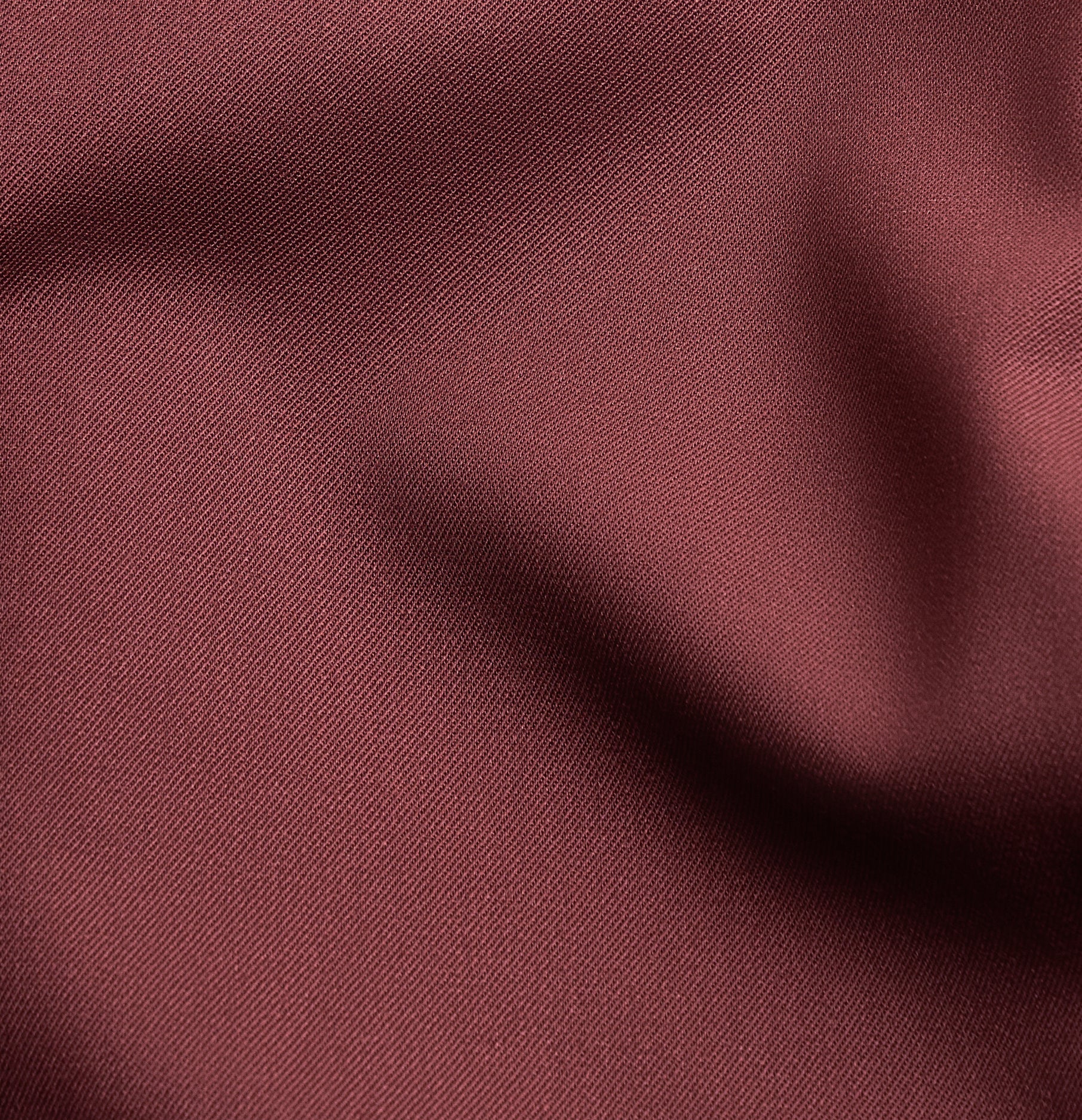 Close-up of textured burgundy fabric with folds and creases.
