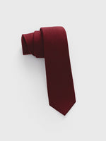 Burgundy tie rolled up on a white background.